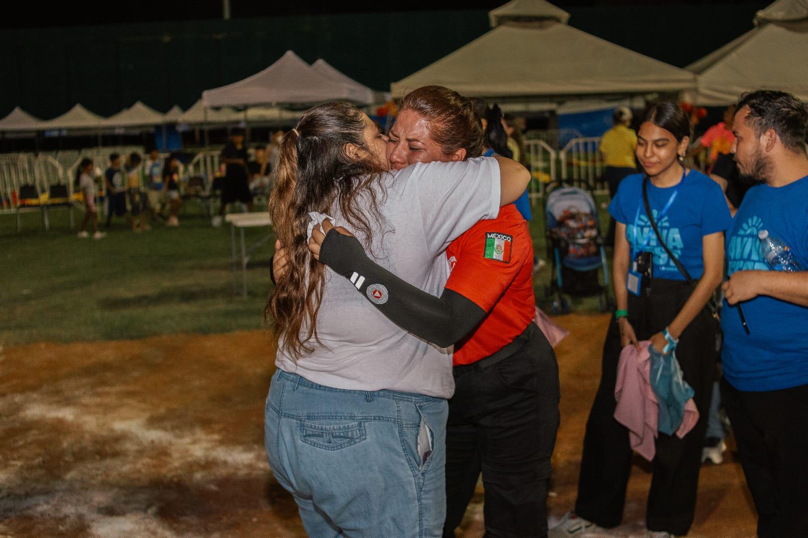Two women embracing in prayer and encouragement during an evening outreach gathering