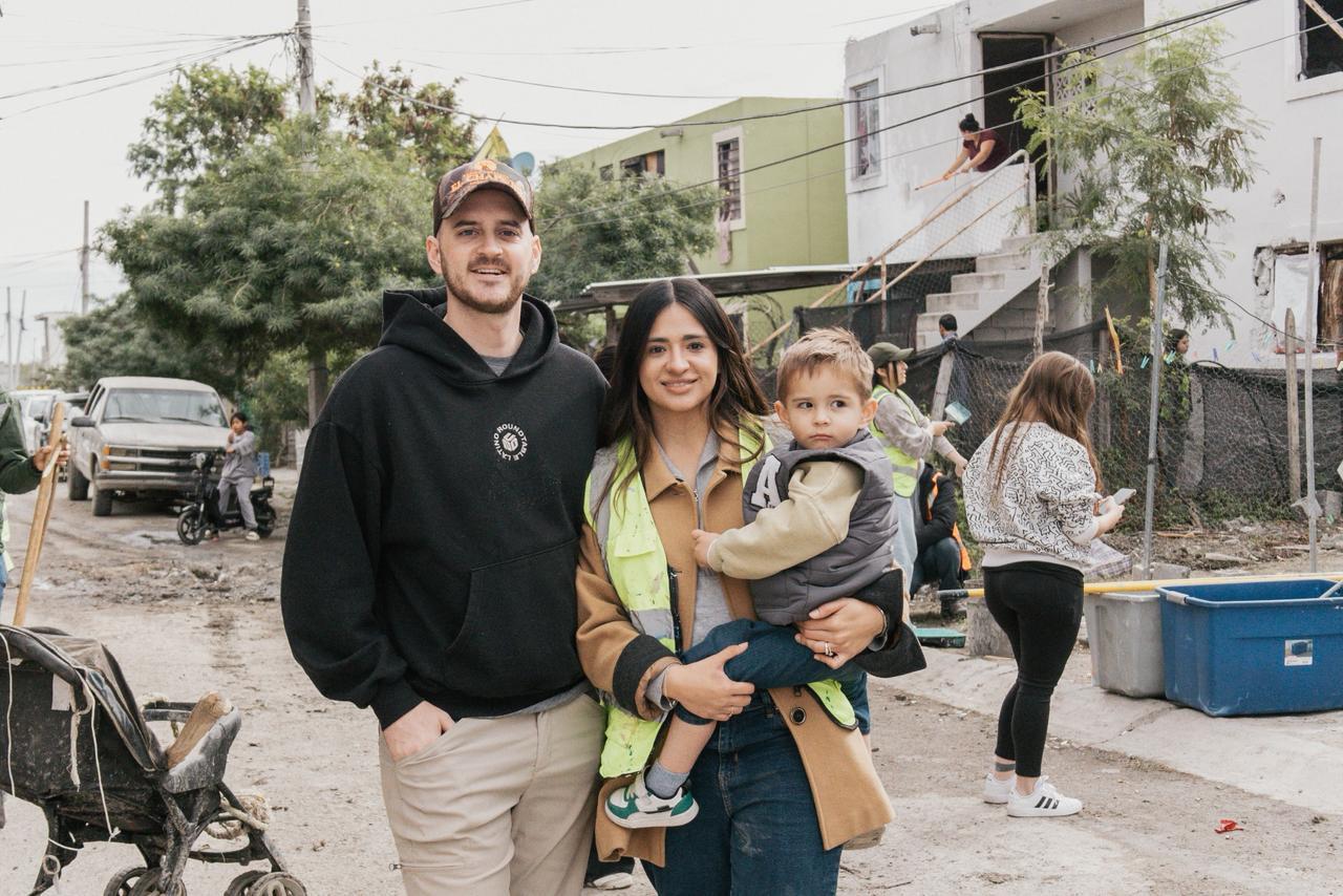 Two ministry leaders holding their young son during a neighborhood outreach project